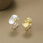 Gold and silver flower-shaped rings on a beige background