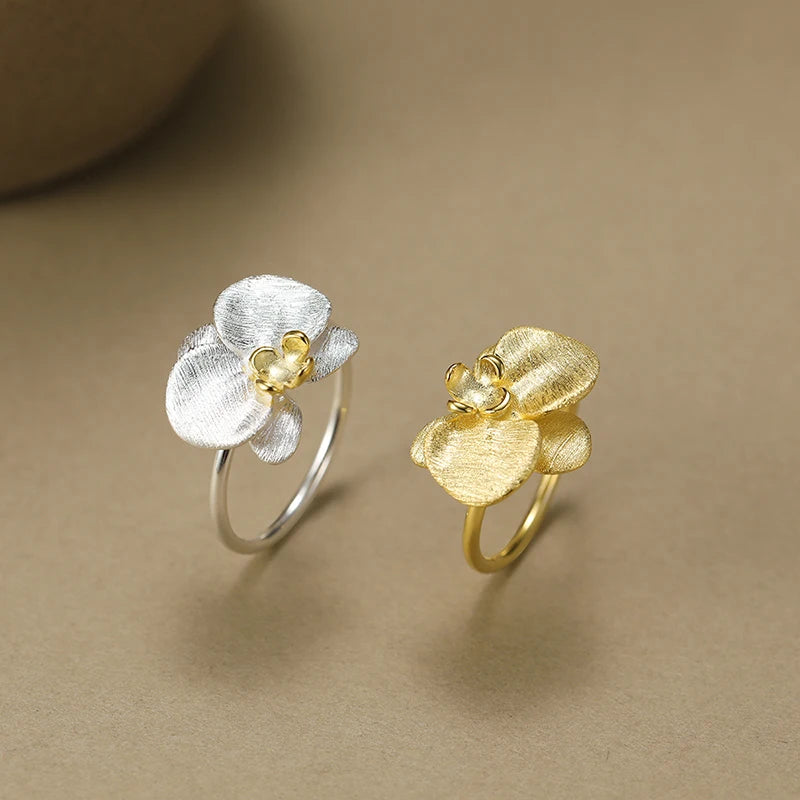 Gold and silver flower-shaped rings on a beige background